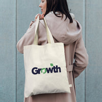 Person holding a conference tote bag with 'Growth' logo against a gray background
